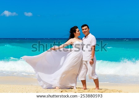 Asian bride and groom on a tropical beach. Wedding and honeymoon concept.