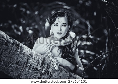 Black and white portrait of the beatiful girl with dangerous snake in the tropical jungle