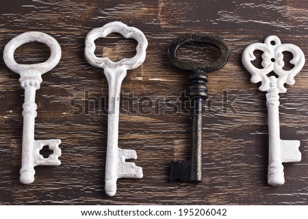 Set of four antique keys, one being different, on a wooden background