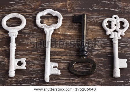 Set of four antique keys, one being different and upside down, on a wooden background