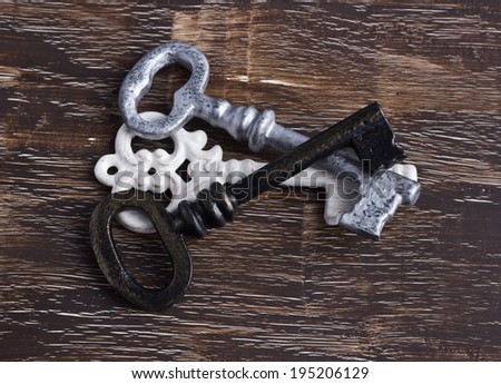 Pile of antique keys, white, silver and brass, on wood background