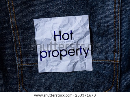 The inscription on the crumpled paper on jeans background. Hot property