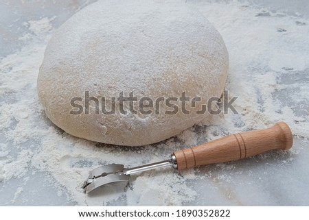 Freshly risen classic French boule bread dough on a marble pastry board with a lame, getting ready for scoring Foto d'archivio © 