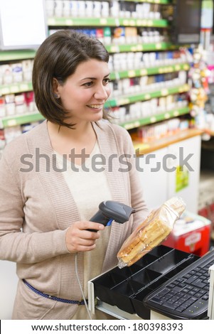 Young woman at cash register in a store using price scanner