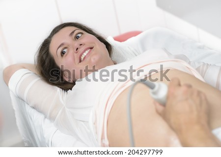 Doctor doing 3d ultrasound on belly of pregnant woman in clinic