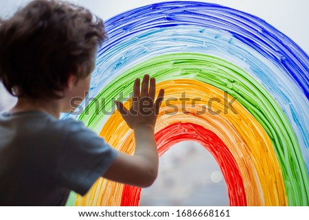 Chase the rainbow. child at home draws a rainbow on the window. Autism Awareness Day, 2 April.  quarantine pandemic coronavirus. Children create artist paints creativity vacation