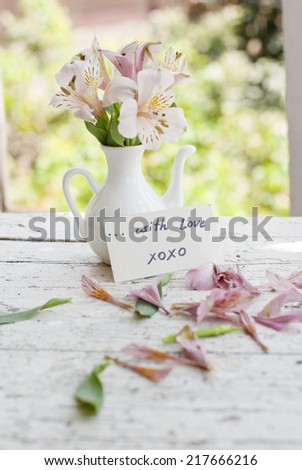 Pink Astromeria flowers in a white jar vase with good morning note spread around