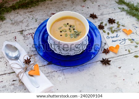 Pumpkin cream soup in a bowl  on a vintage plate with seeds and spices and good morning note, card