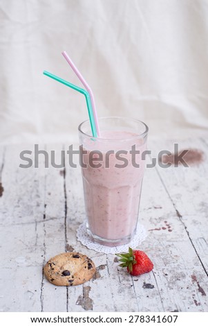 Banana and strawberry delicious smoothie with yogurt, on a wooden shabby background with two straws - mint and pink
