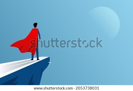 Businessman standing at cliff wearing red cape as superhero, business ambition and courage