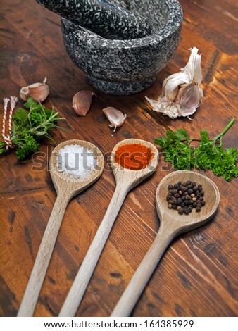 Tree spoons with spices, garlic and a bundle of herbs, mortar and pestle