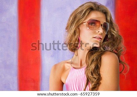 Portrait of an attractive young female in sunglasses posing against colored background