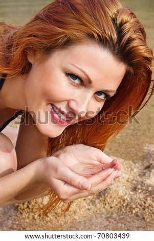 Closeup portrait of a happy young female washing her face with water on the beach - Outdoor