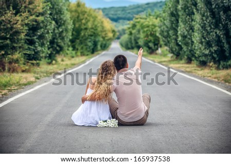 Couple of teenagers sit in street together