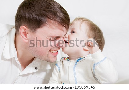Little cute baby biting nose of his father