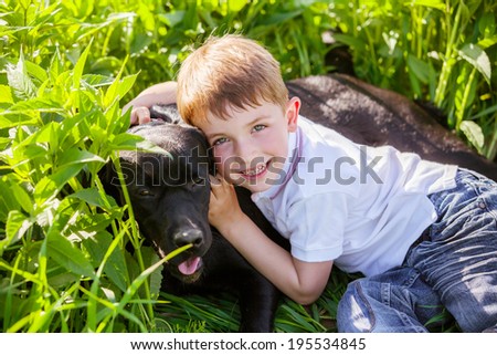 Little boy hugging a big dog in an outdoor setting