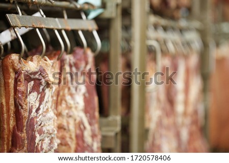 Meat factory. Industrial processing of meat. Slaughterhouse. Cuts of meat hanging on hooks in butchers Сток-фото © 