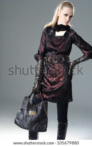 Vogue style fashion model with bag posing on light background