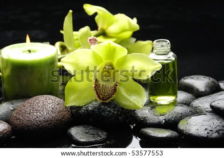 Macro of orchid and massage oil and candle with water drops