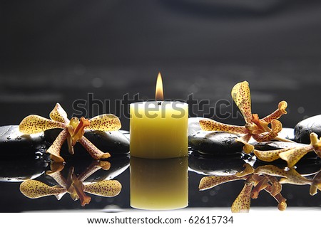 tranquil spa scene - aromatherapy candle and zen stones with yellow orchid