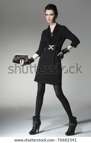 fashion model holding little purse posing in light background