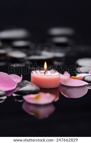 Still life with white rose petals with candle on pebbles