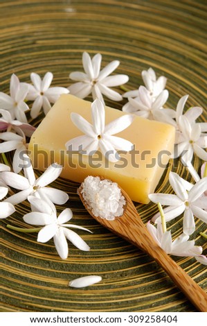 White flower with soap salt in spoon in wooden bowl