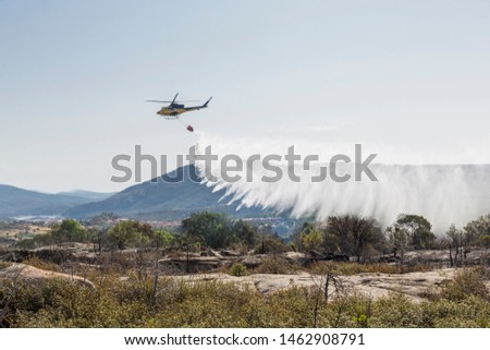 Similar – Image, Stock Photo A firefighting helicopter pours water into a forest to put out a forest fire