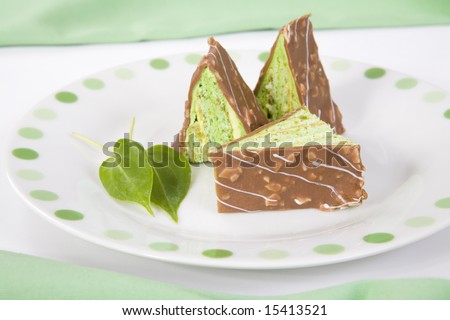 Three green triangular pieces of cake with chocolate on a green spotted plate