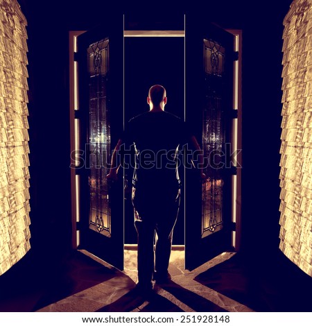 Man opening closing front double entryway doors with glass in foyer at night from behind looking curious afraid creepy welcoming leaving entering the unknown darkness possibility ready for the future