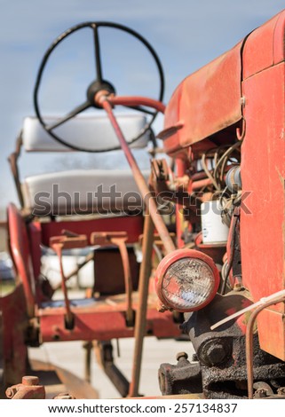 Old vintage antique red farm working tractor outside in the sun on a clear day