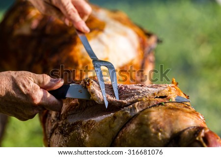 Roasting lamb barbecue - Roasted meat over an open fire - Woman cutting meat