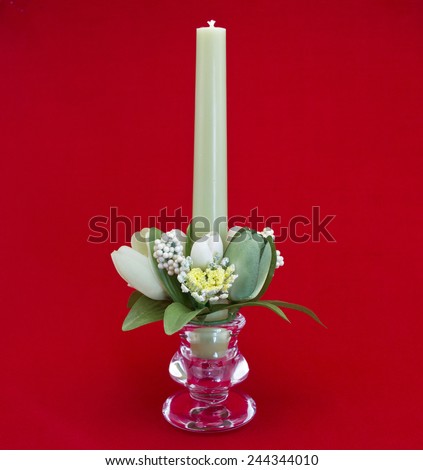Candle holder with green pillar candle against red background