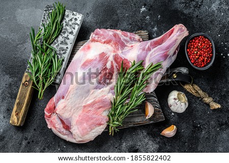 Raw lamb shoulder meat ready for baking with garlic, rosemary. Black background. Top view