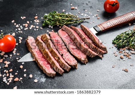 Grilled and sliced flat iron rare steak. Marble beef meat. Black background. Top view ストックフォト © 