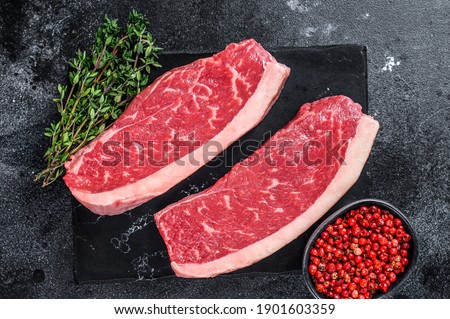 Raw cap rump steak or top sirloin beef meat steak on marble board. Black background. Top view.