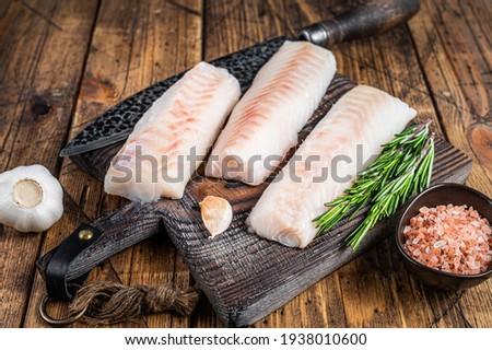 Fresh Raw cod loin fillet steaks on wooden board with butcher knife. wooden background. Top view Stockfoto © 