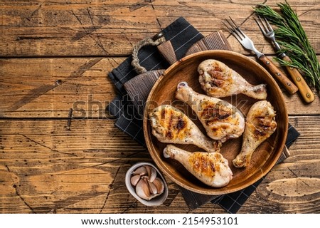 Barbecued Chicken leg drumstick, poultry meat in a wooden plate. Wooden background. Top view. Copy space Stock fotó © 