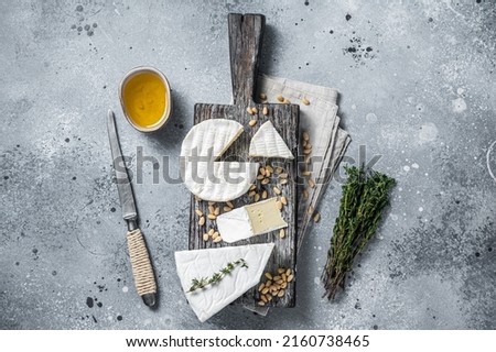 Delicious cheese brie and camembert on wooden board with herbs and nuts. Dairy French products. Gray background. Top view. Foto stock © 