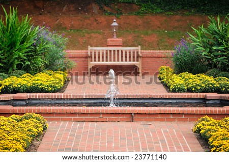 Beautiful Red Brick Walkway and Flower Garden with Water Fountain and Wooden Bench