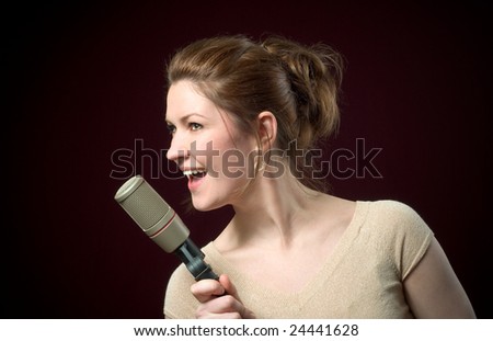 Beautiful Redhead Model Singing into Gold Microphone on deep red background