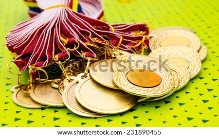 Many gold medals waiting for the winners on a green background