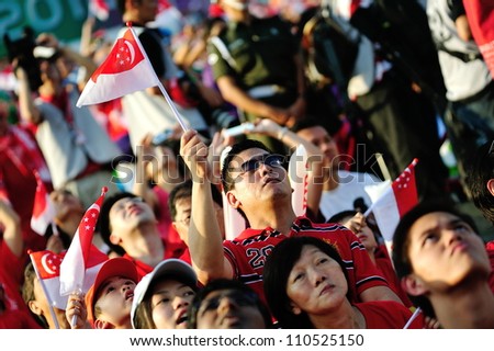 SINGAPORE - AUGUST 09: Audience waving Singapore flags during National Day Parade 2012 on August 09, 2012 in Singapore