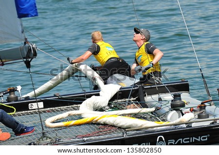 SINGAPORE - APRIL 13: Crew of SAP Extreme Sailing Team steering boat at the Extreme Sailing Series race at Marina Bay Reservoir April 13, 2013 in Singapore