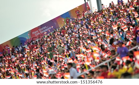 SINGAPORE - JULY 20: Spectators waving Singapore flags during National Day Parade (NDP) Rehearsal 2013 on July 20, 2013 in Singapore