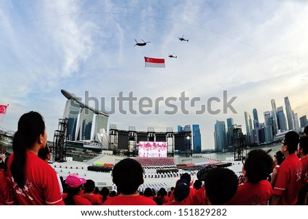 SINGAPORE - JULY 20: Spectators standing at attention as the national flag flypast during National Day Parade (NDP) Rehearsal 2013 on July 20, 2013 in Singapore
