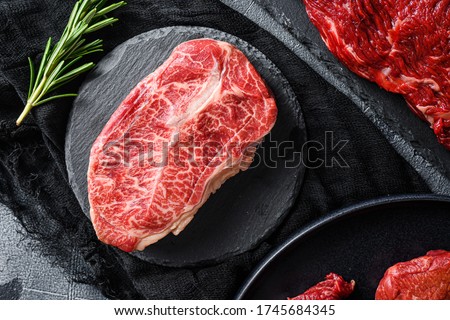 Raw top blade cut black angus organic steak on a black plate and stone slate with seasonings, herbs grey concrete background. Top view close up. ストックフォト © 