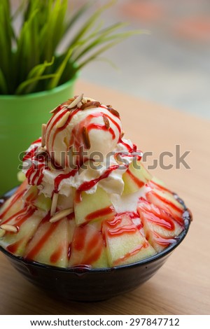 Shaved ice dessert with fresh melon topping with vanilla ice cream, whipped cream, strawberry syrup and almond slices.