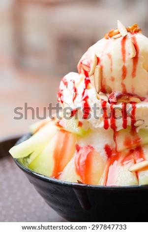 Shaved ice dessert with fresh melon topping with vanilla ice cream, whipped cream, strawberry syrup and almond slices.