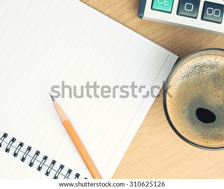 cup of coffee on table with calculators,pencil and book.